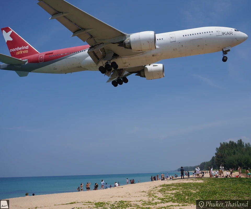 大きな飛行機がビーチの真上を通過する瞬間